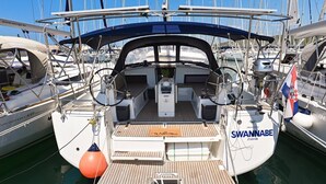 Uno yacht chiamato 'SWANNABE' ormeggiato in un porto turistico con altre imbarcazioni, un cartello con la scritta 'Benvenuti' sul ponte e il logo 'ZADAR'.