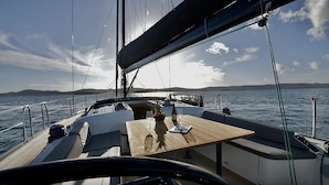 A sailboat's deck with a table, chairs, and a view of the sea and distant land. - Sun-kissed Sailing Adventure in Split-Dalmatia, Croatia (Seget Donji)