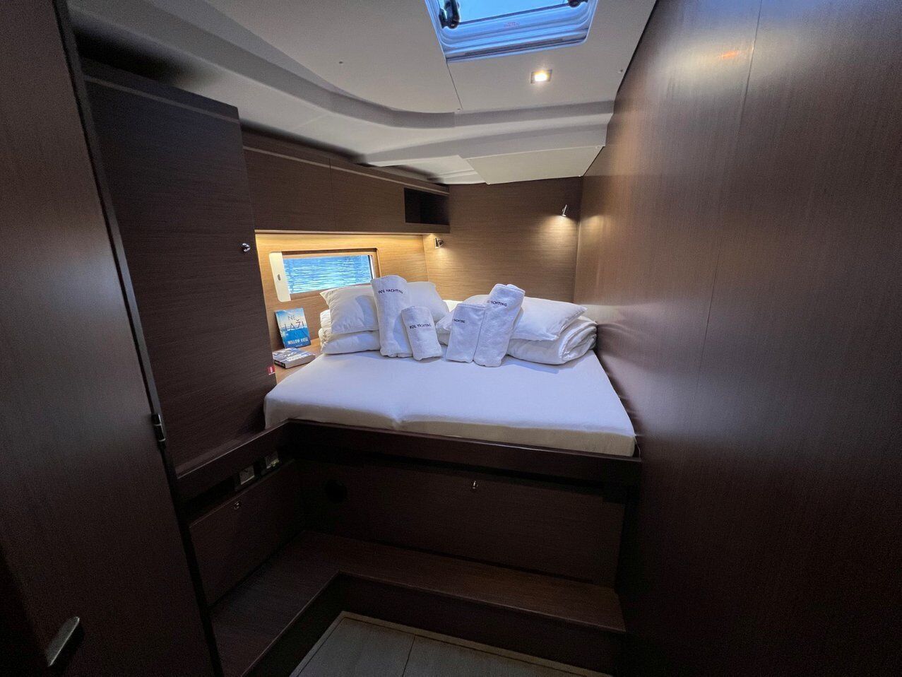 A compact, well-lit cabin with a bed, a small table, and a window.