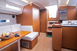 A compact interior with a kitchenette, a dining area with a table and bench, and a small window. - Sun-Kissed Sailing Adventure in Split, Croatia (Split)