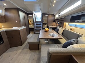 A compact interior with a kitchenette, seating area, and a table with fruit. - Sun-Kissed Sailing Adventure in Istria, Croatia (Pula)