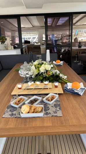 A dining table with food, drinks, and a floral centerpiece in a modern interior. - Sun-Kissed Sailing Adventure in the Ionian Islands (Kallithea)