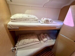Ein Etagenbett mit unterem und oberem Bett, beide mit weißer Bettwäsche und Meeresmotiven.