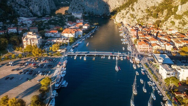 An aerial view of a coastal town with a marina, buildings, and a bridge. - Sun-Kissed Sailing Adventure in Split-Dalmacia, Croatia (Omiš)