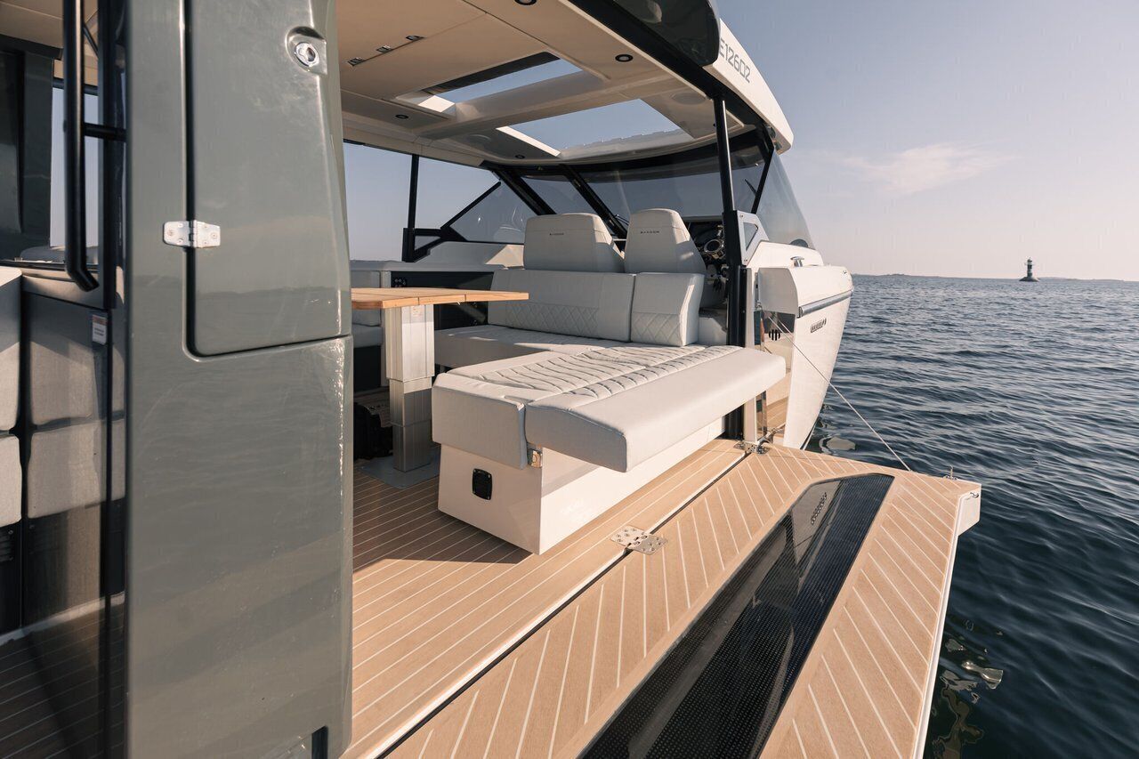 L'intérieur d'un bateau, avec un coin salon, une table et une vue sur l'eau.