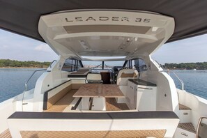 L'intérieur du bateau, un modèle LEADER 36, comprend une table centrale, un coin salon et offre une vue sur l'eau.