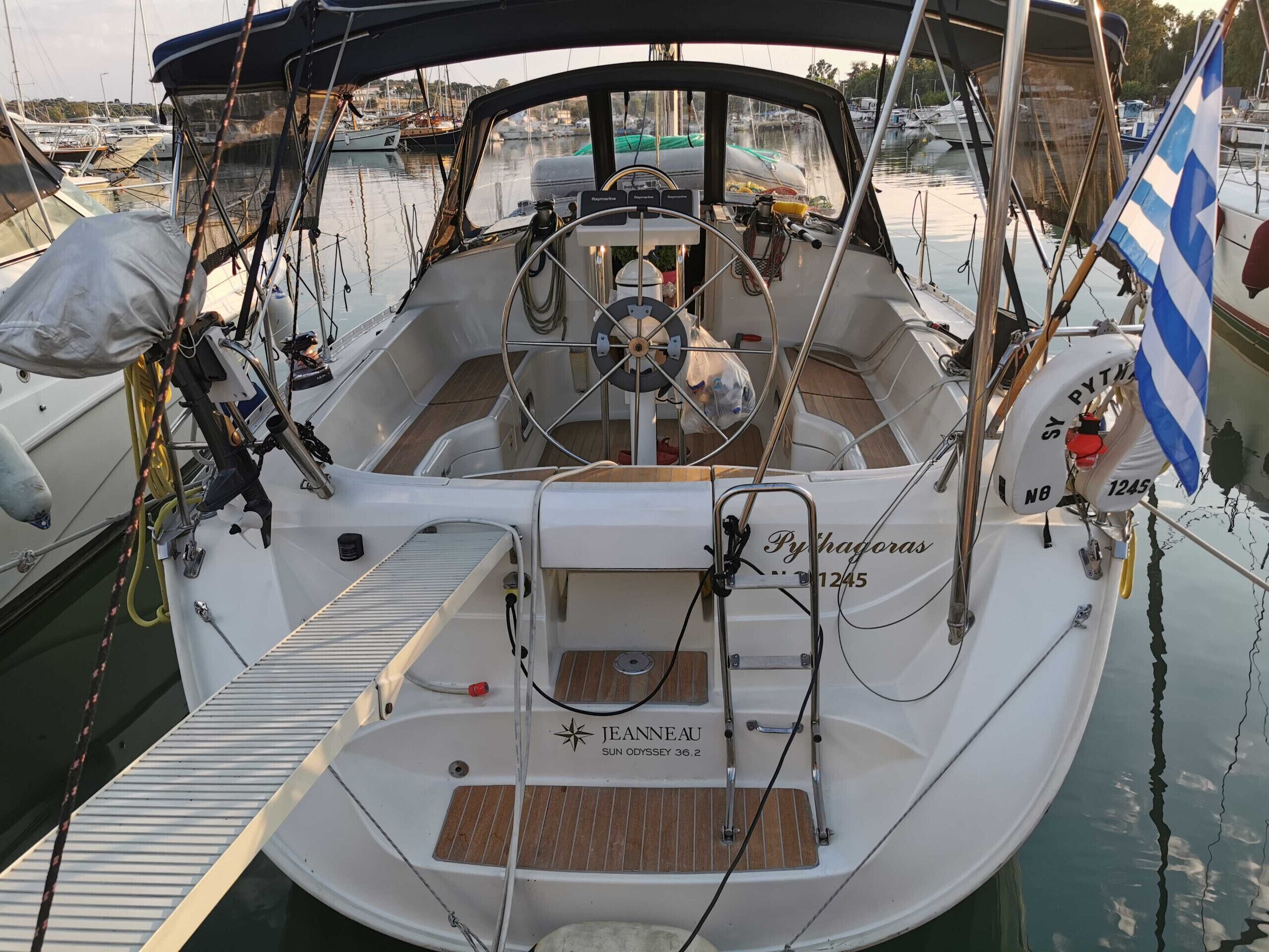 A boat with a steering wheel, a name plaque, and a life buoy.