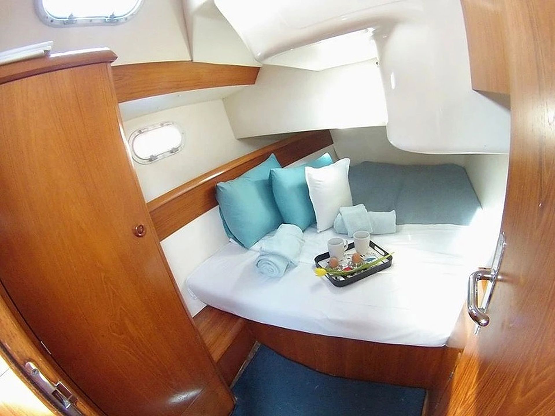 A compact boat interior with a bed, pillows, and a tray with items.