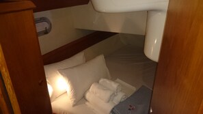 Ein Badezimmer mit Toilette, Waschbecken, Handtuchhalter und einem Bett mit Kissen und einem gefalteten Handtuch.