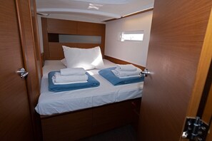 A compact, well-lit cabin with a single bed, neatly folded towels, and a wooden headboard. - Sun-Kissed Sailing Adventure in Split, Croatia (Split)