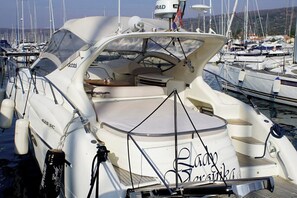 Eine weiße Yacht mit dem Schriftzug 'Radyo Marina' auf dem Bug, liegt in einer Marina, wo weitere Boote vor Anker liegen.