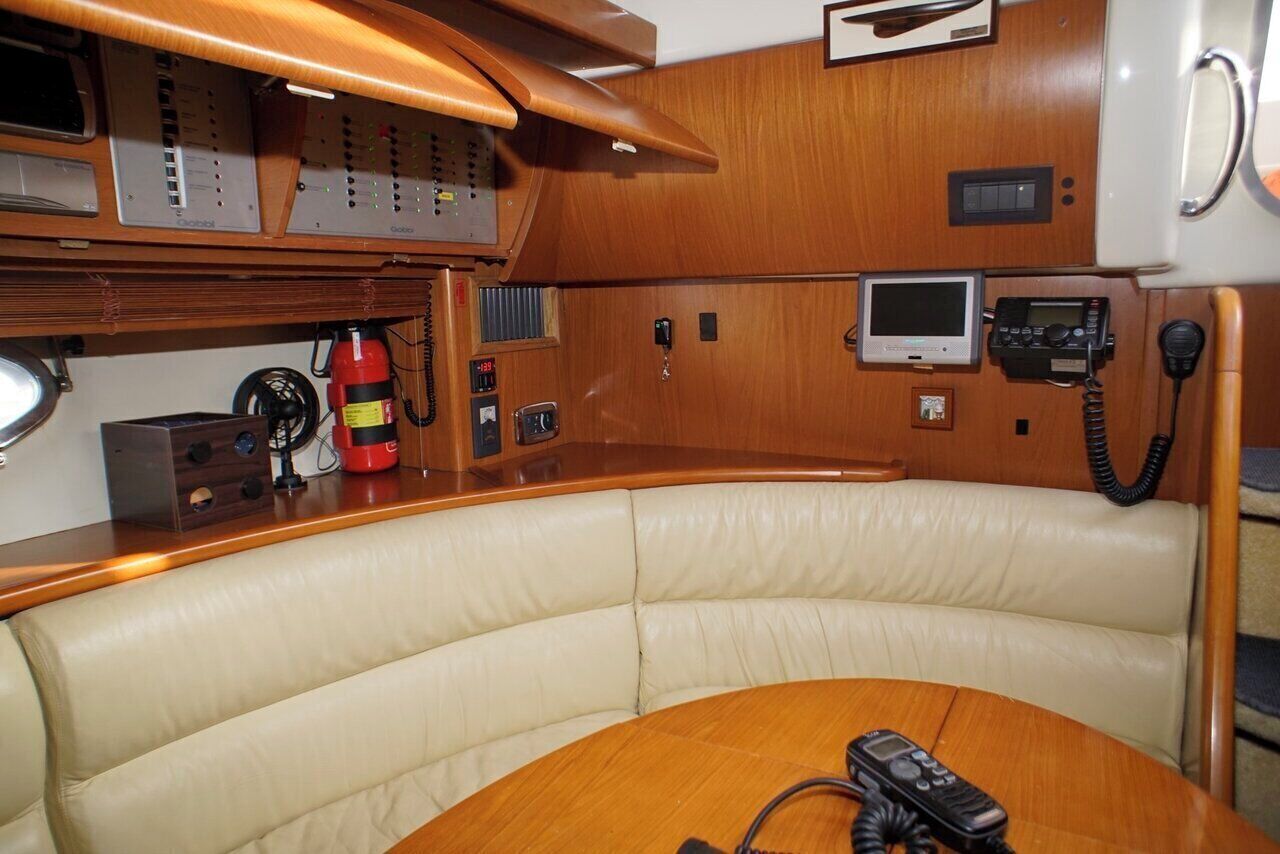 L'intérieur d'un bateau, avec une table en bois, des sièges en cuir, un extincteur et divers panneaux de commande.