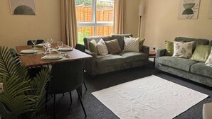 Ein Wohnzimmer mit Esstisch für vier Personen, einer Couch, einer weiteren Couch und einem großen Teppich.