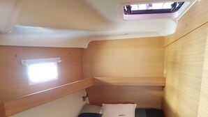 A compact cabin with a bunk bed, a small window, and a skylight.