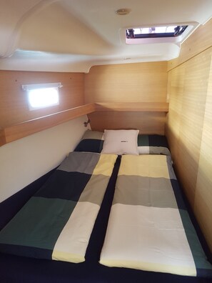 Ein kleines Blockhaus mit einem Einzelbett, einem kleinen Fenster und Holzwänden.