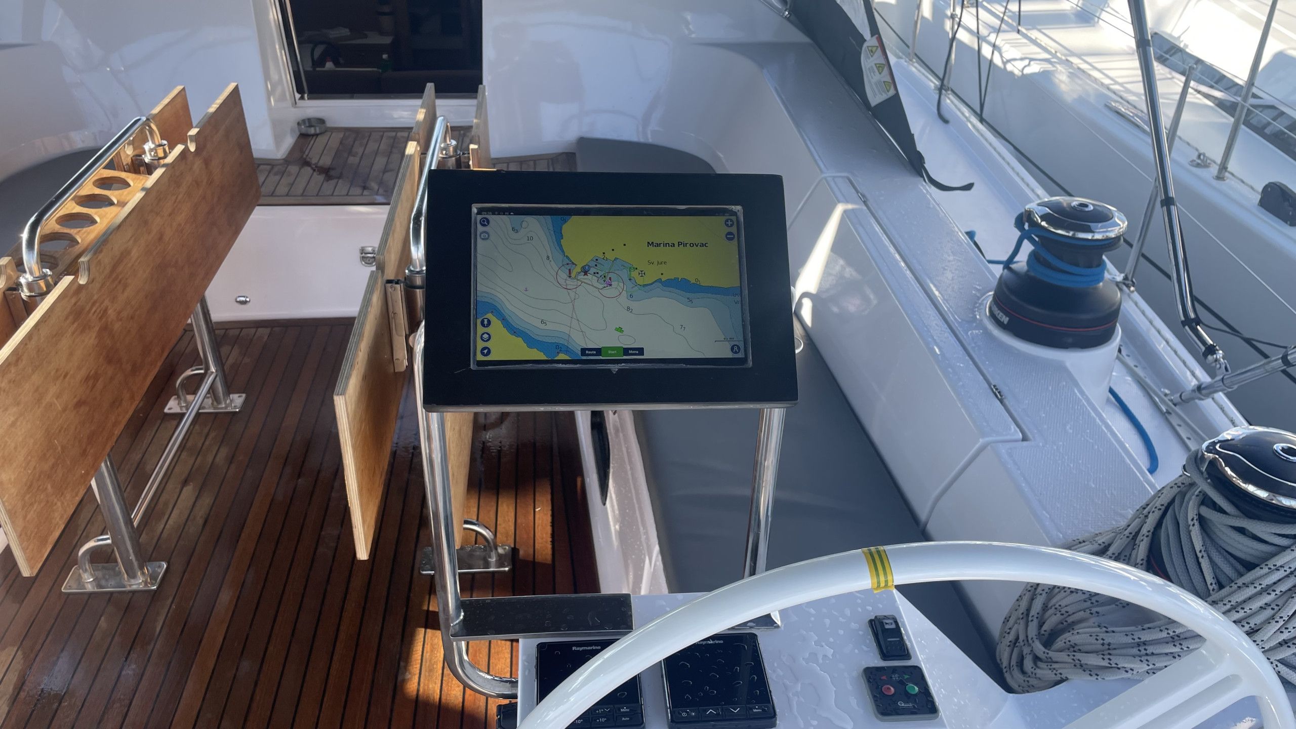 Das Deck eines Bootes mit Navigationsanzeige, Steuerpult und einer hölzernen Sitzbank.