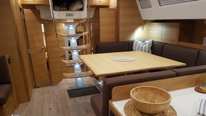 A compact RV interior with a dining area, a sofa, and a small kitchen space.
