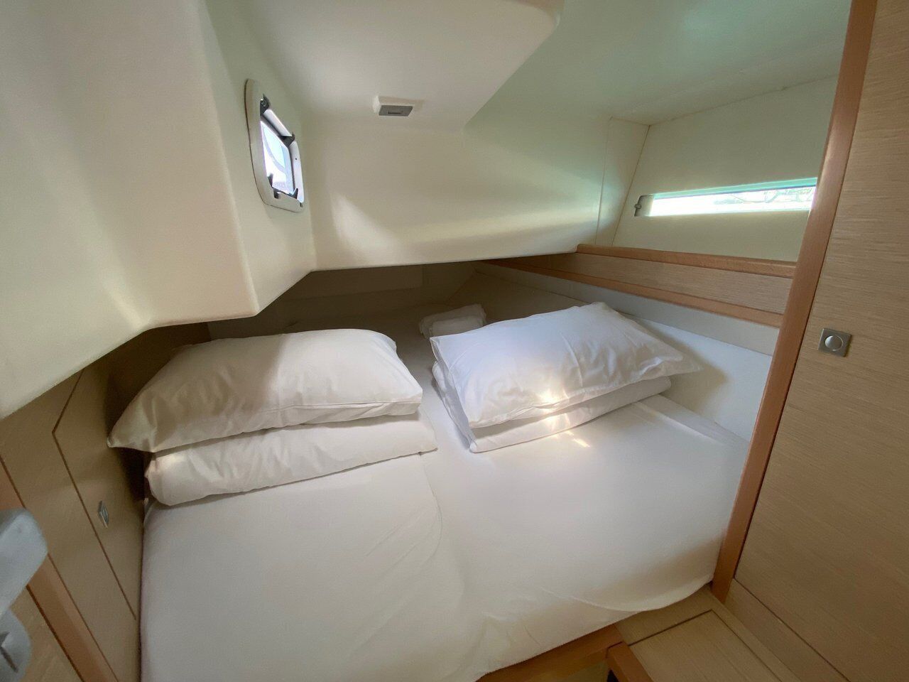 Een compacte, goed verlichte hut met een stapelbed, een klein raam en een deur.