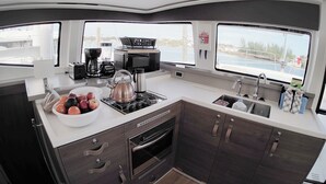 Una cocina compacta con cafetera, hervidor y un bol de fruta.
