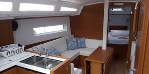 A compact galley with a sink, a small wooden table, and a sofa with patterned cushions.