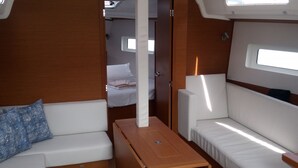 A compact interior with a sofa, a small table, and a bed in the background.
