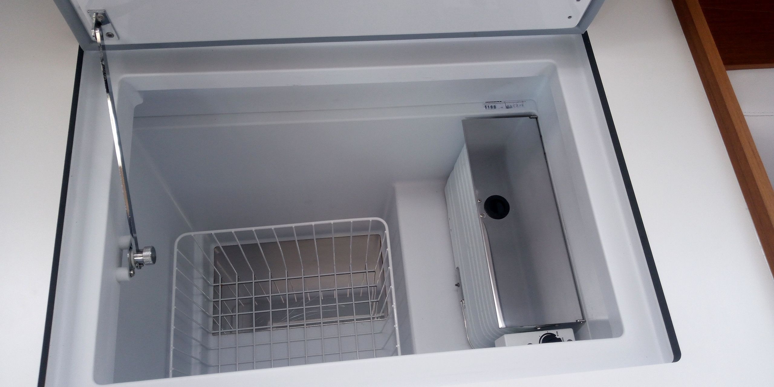A white, empty room with a metal rack and a small, rectangular object on the floor.