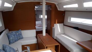A compact interior with a sofa, a small table, and a bench. There are windows providing natural light.