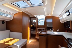 A compact interior with a kitchenette, seating area, and a small window. - Dubrovnik Delight: A Sun-Kissed Sailing Experience (Komolac)