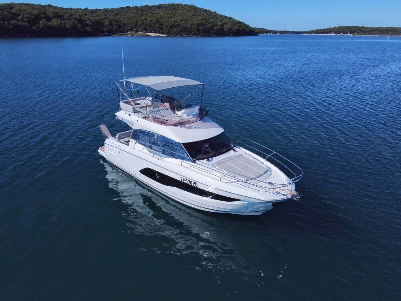 A white yacht with a covered upper deck, a cabin, and a motorized outboard.