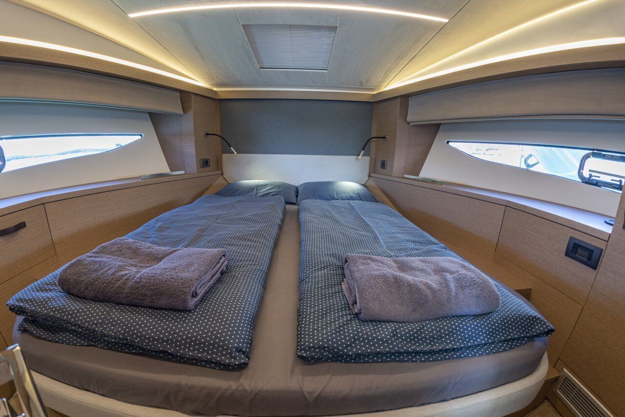 A cabin with two beds, each with a pillow and a blanket, and a window on one side.