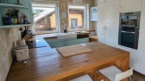 Ett kök med en köksö i trä, vita skåp och utsikt mot omgivningen.