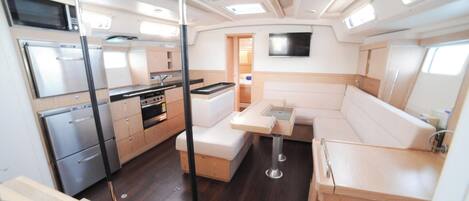 A compact kitchen with a stove, microwave, and cabinets, a dining area with a table and benches, and a small seating area with a sofa.