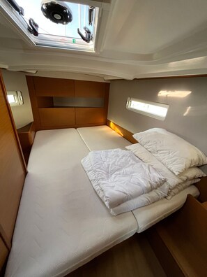 Ein gemütliches, gut beleuchtetes Kabinenzimmer mit einem Einzelbett, einem kleinen Fenster mit Ausblick und einer festen Kopfstütze.