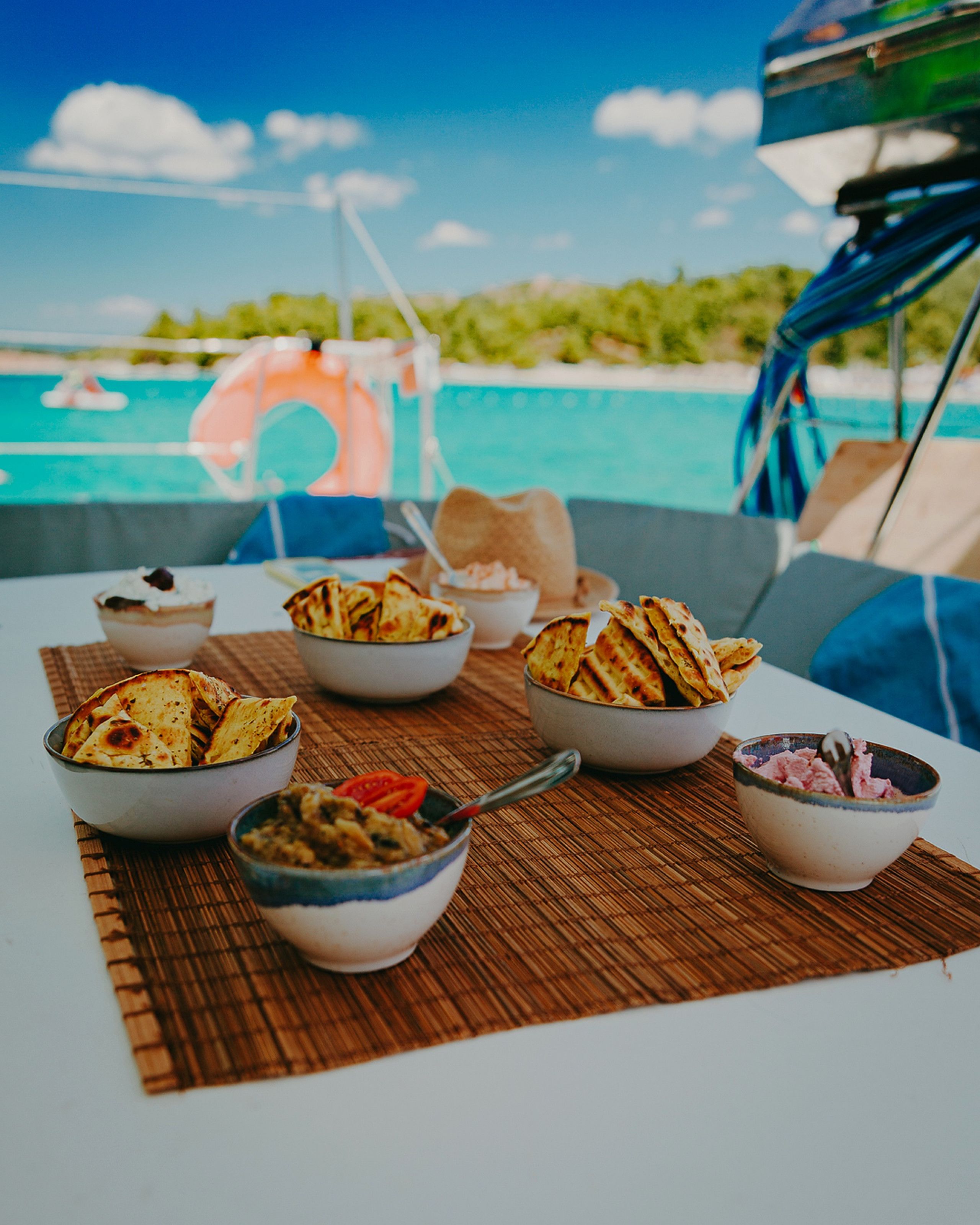 A table with various food items and a view of the ocean and sky.