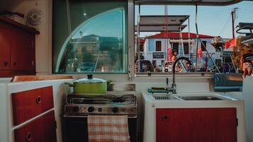 Une petite cuisine équipée d’une cuisinière, d’un évier et d’une fenêtre donnant sur la rue.