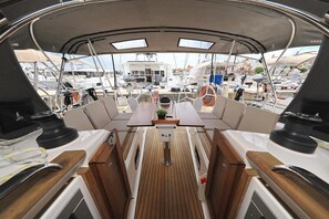 A boat deck with a central table, seating, and a view of other boats. - Sun-Kissed Sailing Adventure in Zadar, Croatia (Biograd na moru)