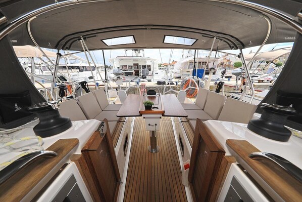 A boat deck with a central table, seating, and a view of other boats. - Sun-Kissed Sailing Adventure in Zadar, Croatia (Biograd na moru)