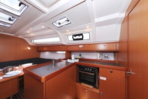 A compact galley with a stove, sink, and storage cabinets, featuring skylights and a view of the deck. - Sun-Kissed Sailing Adventure in Zadar, Croatia (Biograd na moru)
