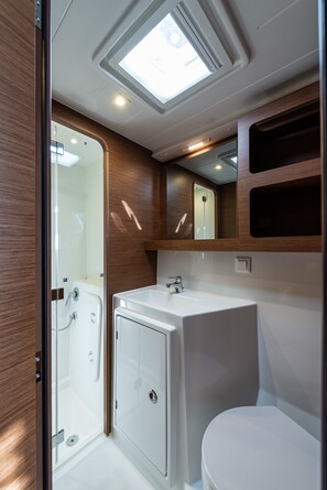 A compact bathroom with a shower, toilet, and sink, featuring a skylight and wooden paneling. - Sun-Kissed Sailing Adventure in the Ionian Islands, Lefkada (Lefkada)