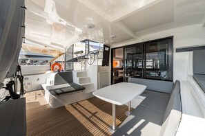 A sunlit deck with a table and seating, a lifebuoy, and a view of the water. - Sun-Kissed Sailing Adventure in the Ionian Islands, Lefkada (Lefkada)
