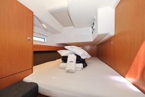 Ein gemütliches, helles Kabinenzimmer mit einem Etagenbett, einer kleinen Bank und ordentlich gefalteten Handtüchern.