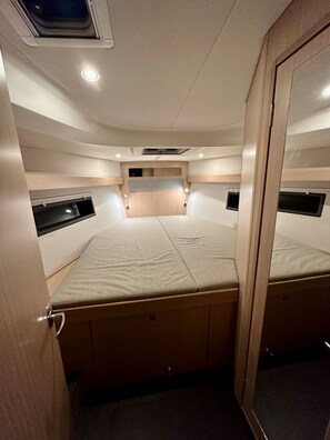 Ein kompakter, gut beleuchteter Raum mit einem zentral platzierten Bett, Nachttischen und einer integrierten Sitzbank.