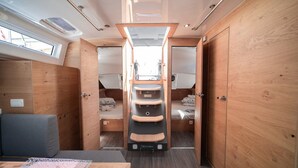 Interior compacto de una caravana con zona de descanso central, una pequeña cocina y un ventanal que proporciona luz natural.
