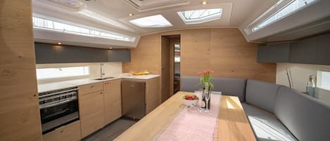 Una cucina compatta con isola centrale, forno integrato e zona pranzo con una panca.