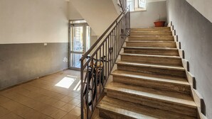 Una escalera con barandillas metálicas, piso de baldosas y una puerta que da a otra habitación.