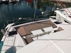 A boat deck with seating areas, a railing, and a view of the water.