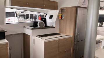 Une cuisine compacte dotée d’un évier encastré, d’une petite cuisinière et d’un réfrigérateur.