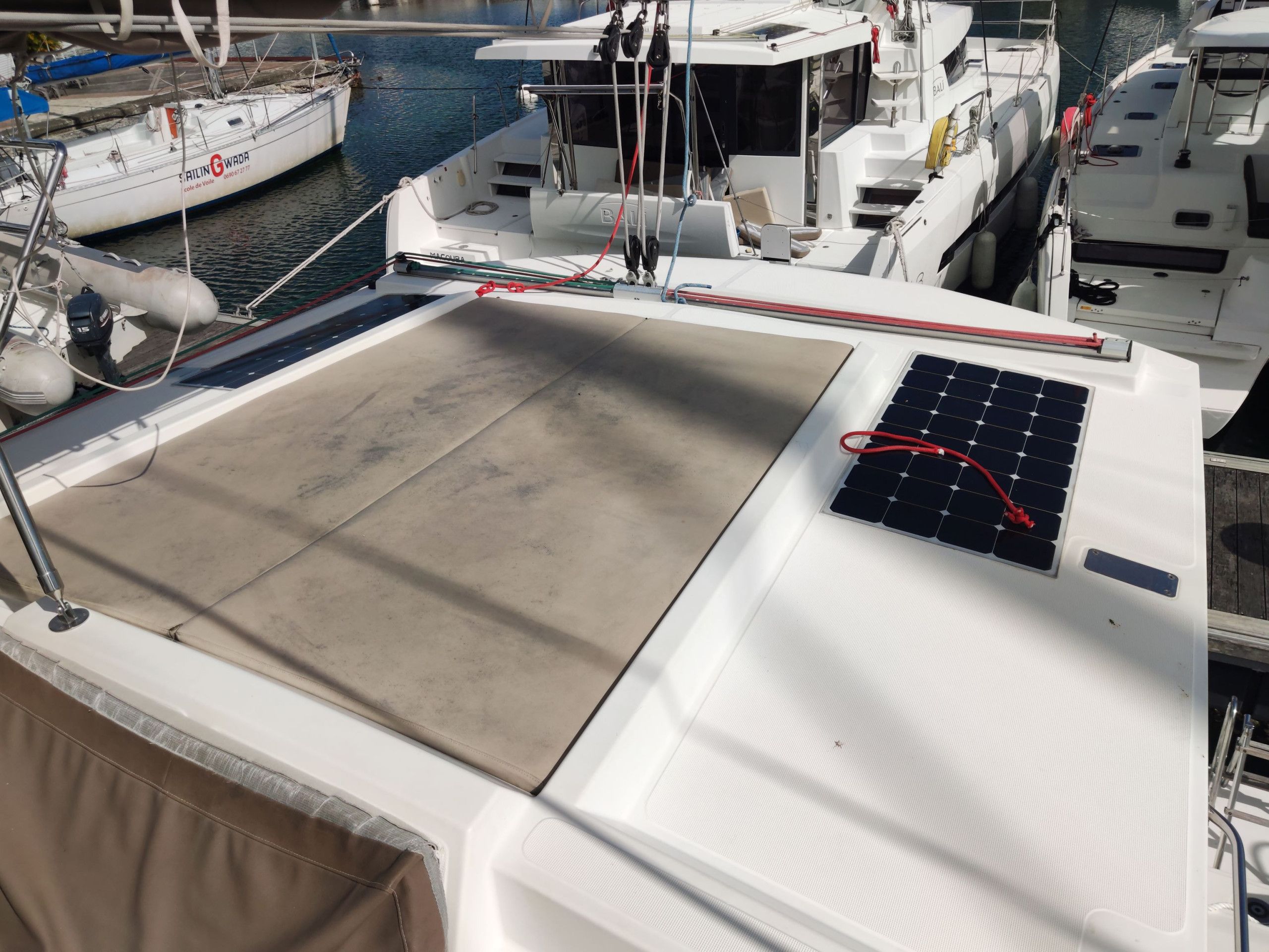 Un pont de bateau équipé d’un panneau solaire, une cabine blanche et une voie navigable où d’autres bateaux circulent.