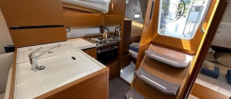 A compact galley with a sink, stove, and storage cabinets.