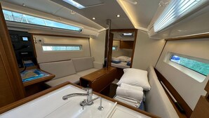 A compact, well-lit interior with a sink, a small table, a bed, and a control panel. - Dubrovnik Delight: A Sun-Kissed Sailing Experience (Komolac)